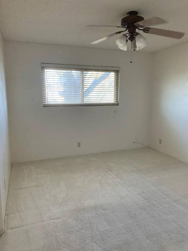 spare room with a ceiling fan and light colored carpet