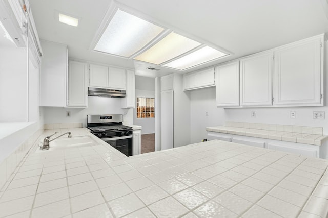 kitchen featuring gas stove, a sink, white cabinets, and under cabinet range hood