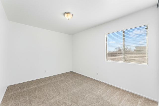 carpeted spare room featuring baseboards