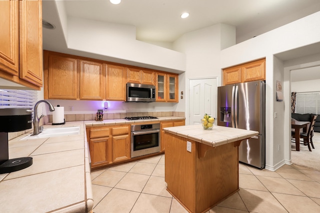 kitchen featuring tile counters, a center island, light tile patterned floors, and appliances with stainless steel finishes