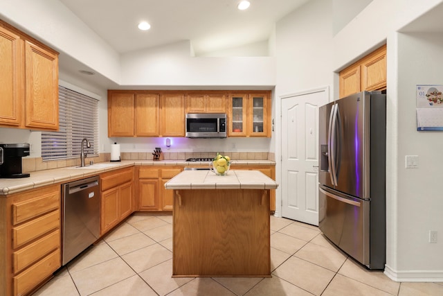 kitchen featuring stainless steel appliances, sink, light tile patterned floors, tile countertops, and a center island