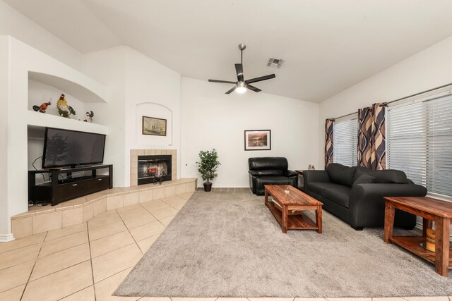 living room featuring ceiling fan, a fireplace, light tile patterned flooring, and vaulted ceiling