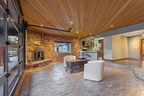 living room with wood ceiling, a fireplace, and brick wall