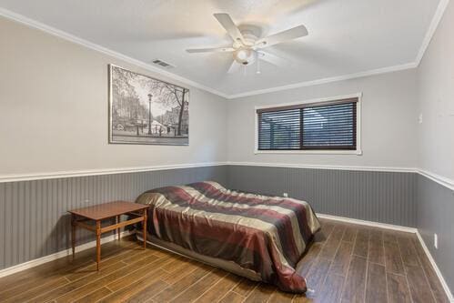 bedroom with crown molding, ceiling fan, and dark hardwood / wood-style flooring