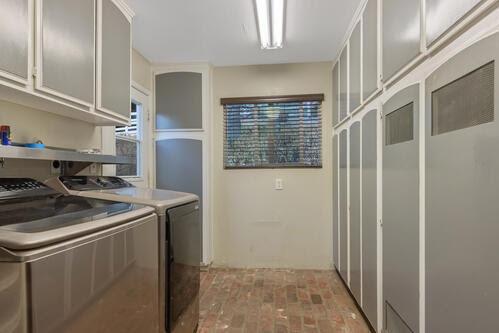 clothes washing area with washer and clothes dryer and cabinets