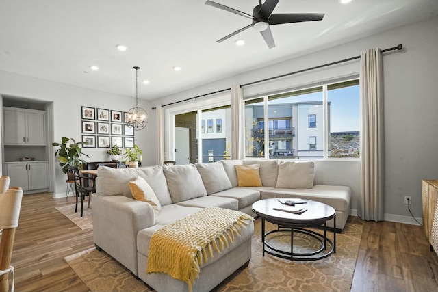 living room with dark wood-type flooring and ceiling fan with notable chandelier