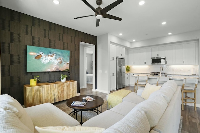 living room with sink, wood-type flooring, and ceiling fan