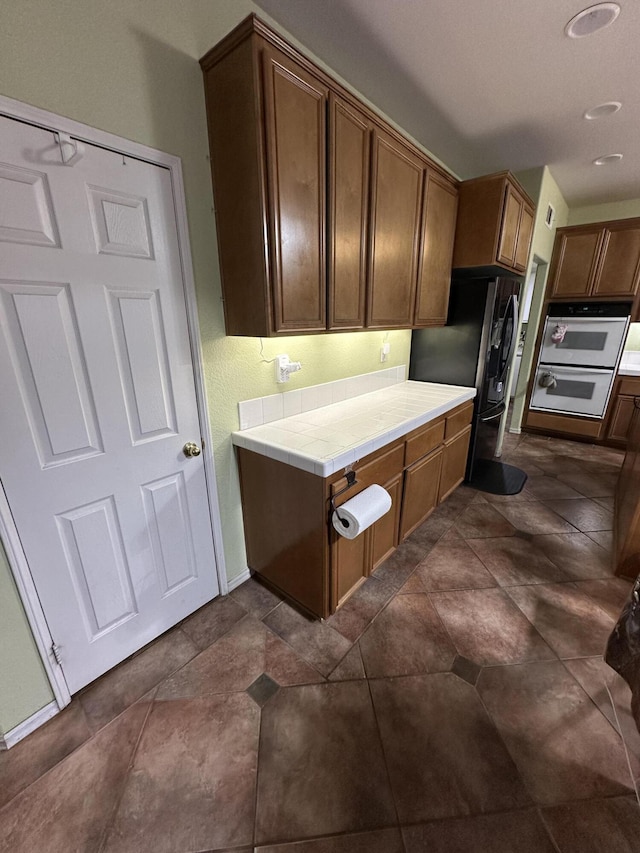 kitchen featuring white oven, black refrigerator, and tile counters