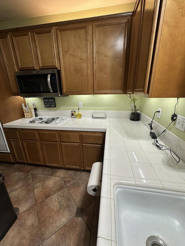 kitchen with tile counters and white gas cooktop