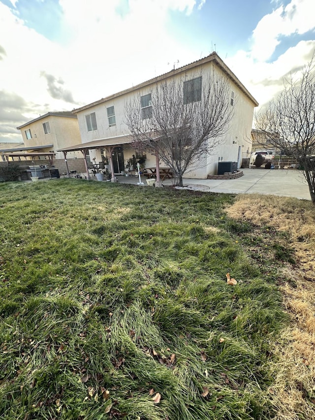 rear view of house featuring central AC unit, a patio area, and a yard