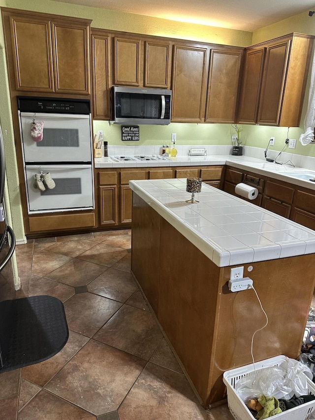 kitchen with tile counters, a center island, and white appliances