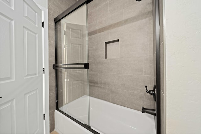 bathroom featuring combined bath / shower with glass door