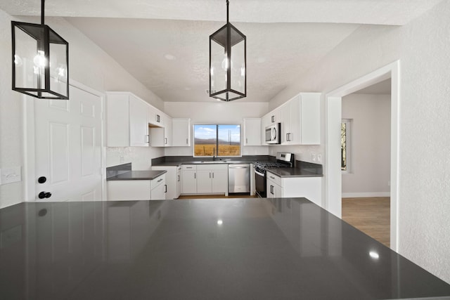 kitchen with appliances with stainless steel finishes, sink, decorative light fixtures, hardwood / wood-style flooring, and white cabinets