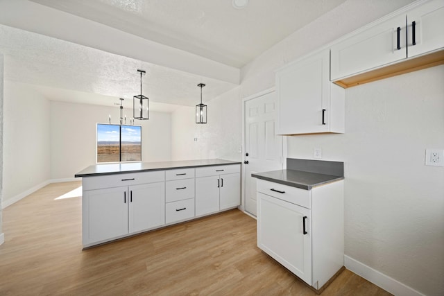 kitchen with kitchen peninsula, white cabinetry, light hardwood / wood-style flooring, and hanging light fixtures