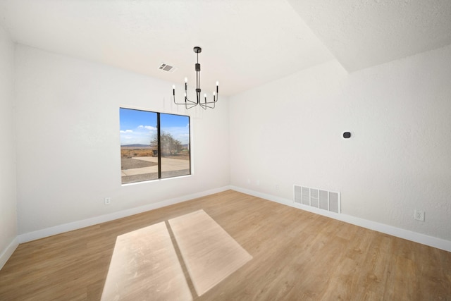 unfurnished dining area featuring wood-type flooring and a notable chandelier