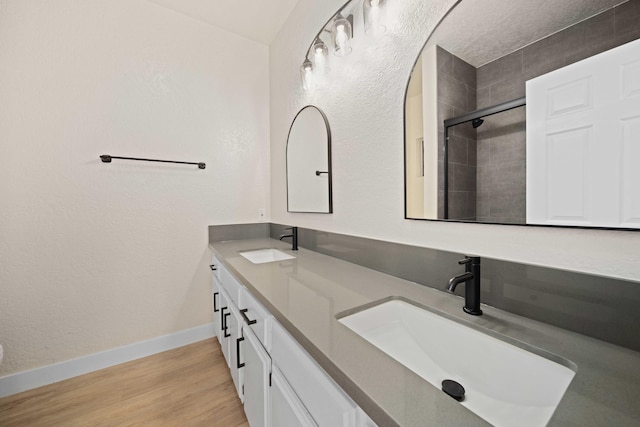 bathroom with hardwood / wood-style floors, vanity, and a tile shower