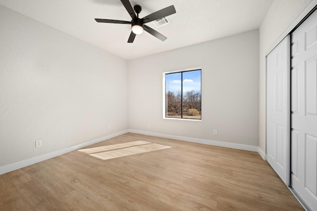 unfurnished bedroom with ceiling fan, a closet, and light wood-type flooring