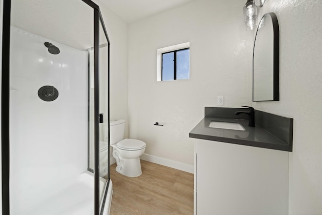 bathroom with a shower, hardwood / wood-style floors, vanity, and toilet