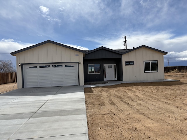 view of front of home with a garage, concrete driveway, and fence