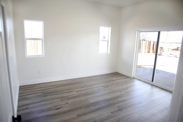 empty room featuring wood finished floors, baseboards, and a wealth of natural light