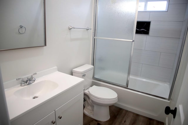 bathroom featuring bath / shower combo with glass door, toilet, vanity, and wood finished floors