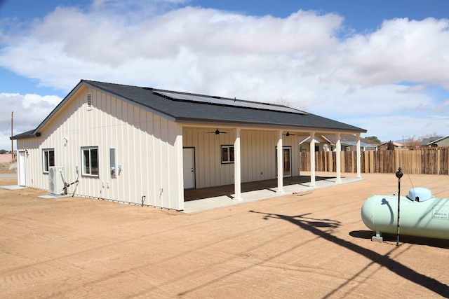 exterior space featuring a patio, fence, solar panels, ceiling fan, and board and batten siding