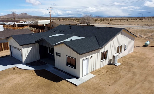 exterior space featuring a garage, a mountain view, board and batten siding, and roof with shingles