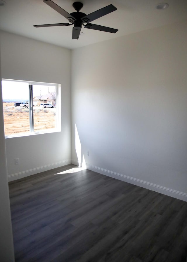 spare room with dark wood finished floors, baseboards, and ceiling fan