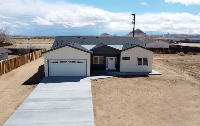 view of front of home with roof with shingles, concrete driveway, an attached garage, and fence