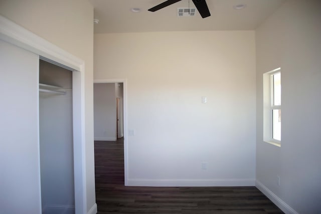 unfurnished bedroom featuring visible vents, dark wood-style floors, baseboards, and a closet