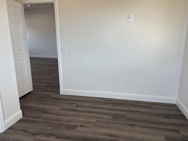 spare room with dark wood-type flooring and baseboards