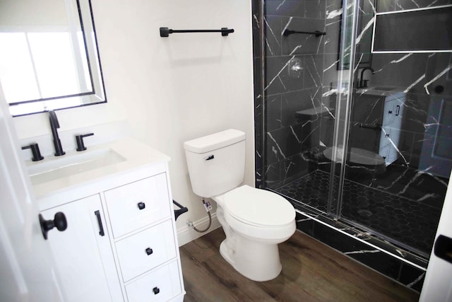 bathroom with a marble finish shower, toilet, wood finished floors, and vanity