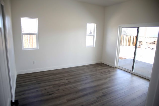 empty room featuring a wealth of natural light, baseboards, and dark wood-type flooring