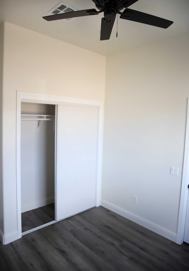 unfurnished bedroom featuring dark wood finished floors, baseboards, a closet, and ceiling fan