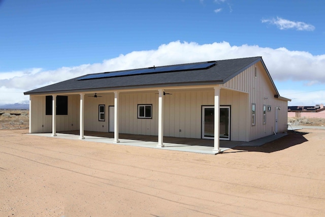 back of property featuring roof mounted solar panels, a patio, a ceiling fan, and board and batten siding
