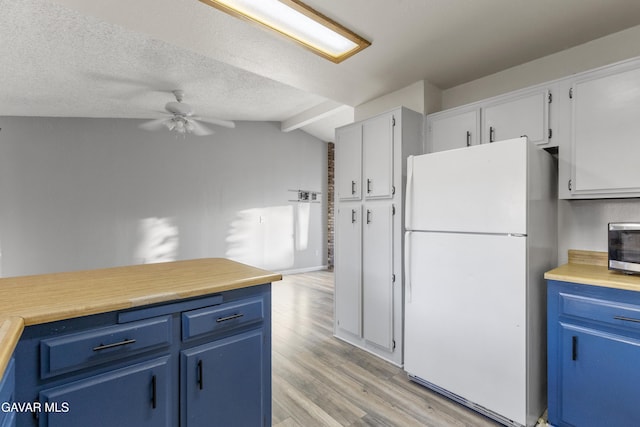 14332 Lear St, Mojave, CA 93501 - kitchen with freestanding refrigerator, blue cabinets, light wood-style floors, ceiling fan, and lofted ceiling