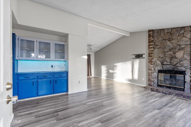 14332 Lear St, Mojave, CA 93501 - unfurnished living room with wood finished floors, a textured ceiling, vaulted ceiling, a fireplace, and ceiling fan