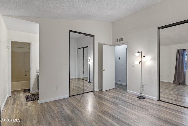 14332 Lear St, Mojave, CA 93501 - unfurnished bedroom with vaulted ceiling, wood finished floors, a textured ceiling, and ensuite bath