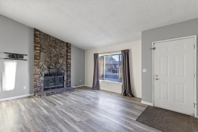 14332 Lear St, Mojave, CA 93501 - unfurnished living room featuring a textured ceiling, a stone fireplace, wood finished floors, and lofted ceiling