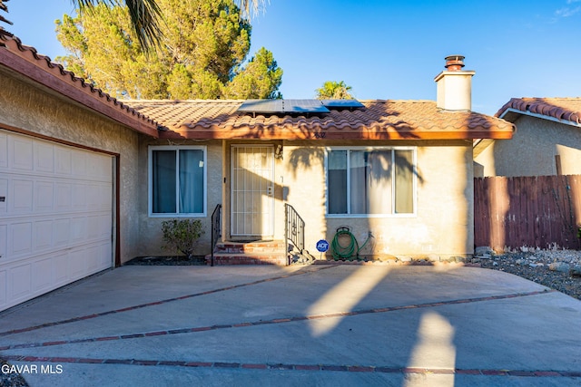 14332 Lear St, Mojave, CA 93501 - view of front of house featuring a tile roof, stucco siding, a chimney, driveway, and roof mounted solar panels
