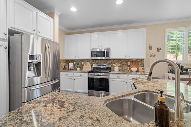 kitchen with white cabinetry, ornamental molding, appliances with stainless steel finishes, and a sink