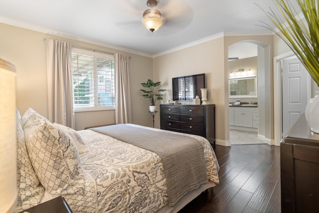 bedroom with ornamental molding, dark wood finished floors, ensuite bath, a sink, and arched walkways