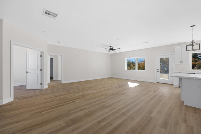 unfurnished living room featuring visible vents, ceiling fan, light wood-style flooring, and baseboards