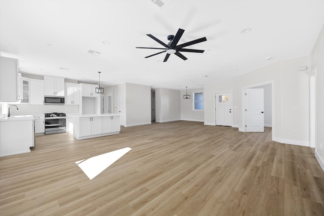 unfurnished living room featuring visible vents, light wood finished floors, a ceiling fan, and baseboards