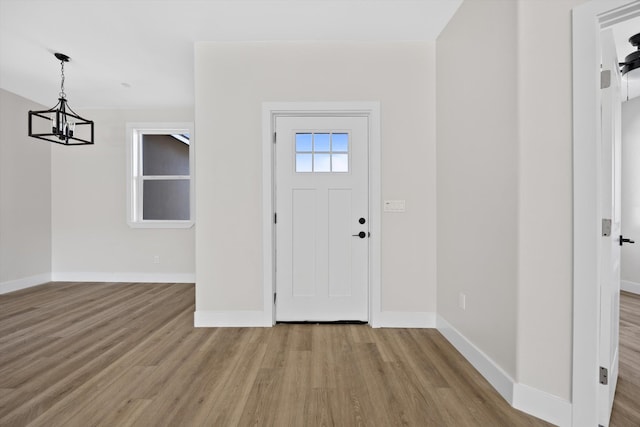 entrance foyer with a chandelier, baseboards, and wood finished floors