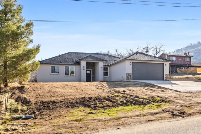 view of front of house featuring driveway, stone siding, a garage, and stucco siding