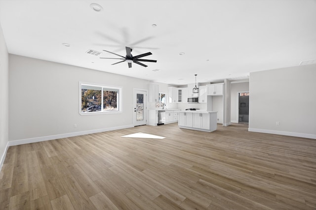 unfurnished living room featuring light wood-style floors, baseboards, visible vents, and a ceiling fan