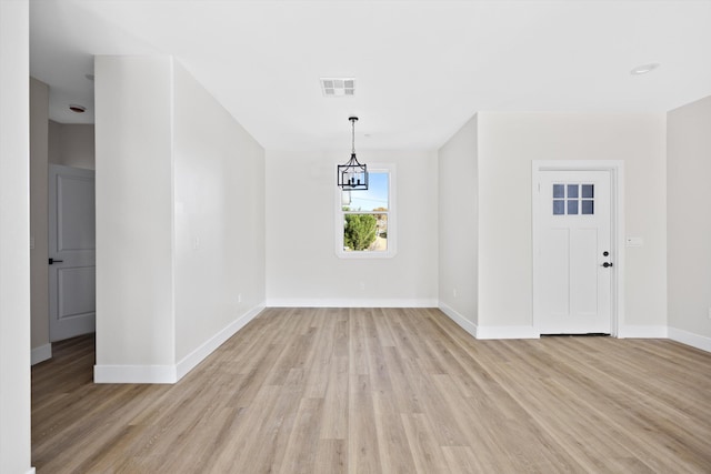 unfurnished dining area with light wood finished floors, visible vents, baseboards, and an inviting chandelier