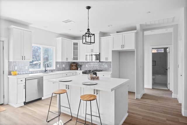 kitchen featuring appliances with stainless steel finishes, visible vents, a sink, and white cabinetry