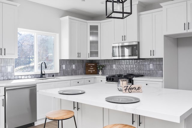 kitchen with white cabinetry, a kitchen island, appliances with stainless steel finishes, and a sink